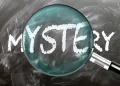 Filmes de mistério de Agatha Christie /Mistério - aprenda, estude e inspecione. Dando uma olhada mais de perto no mistério. Uma lupa ampliando a palavra "mistério" escrita em um quadro negro - imagem de stock